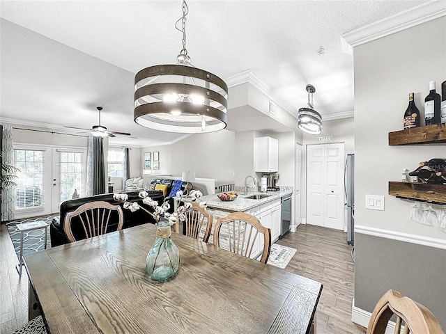 dining space with french doors, crown molding, light hardwood / wood-style flooring, sink, and ceiling fan