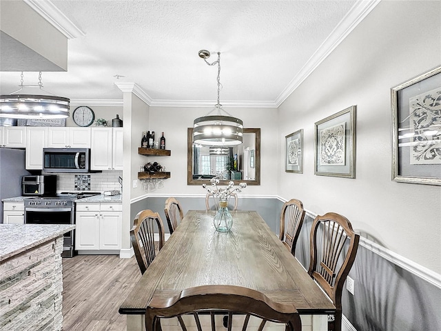 dining space featuring crown molding, light hardwood / wood-style floors, and a textured ceiling