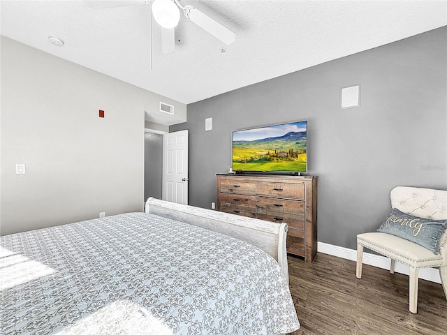 bedroom with dark hardwood / wood-style floors, ceiling fan, and a textured ceiling