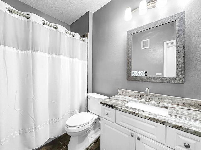 bathroom featuring a textured ceiling, vanity, tile floors, and toilet