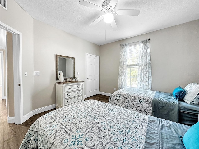 bedroom with ceiling fan, dark hardwood / wood-style floors, and a textured ceiling