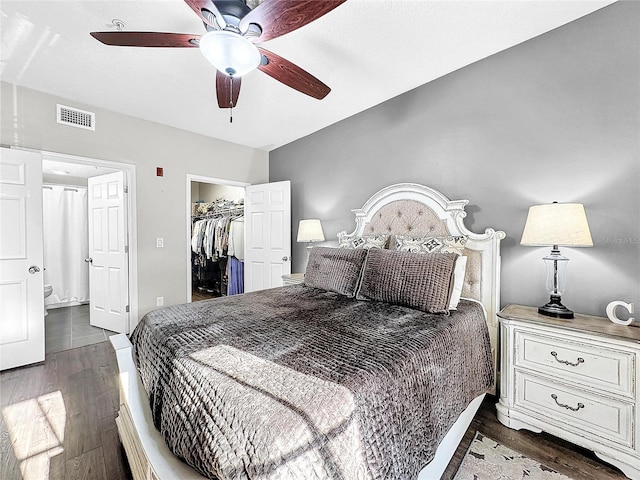 bedroom featuring dark wood-type flooring, ceiling fan, a closet, and a walk in closet