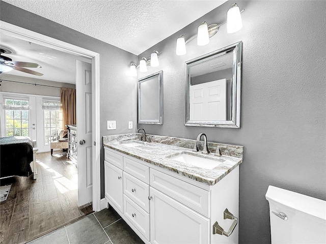 bathroom featuring hardwood / wood-style floors, dual vanity, toilet, ceiling fan, and a textured ceiling