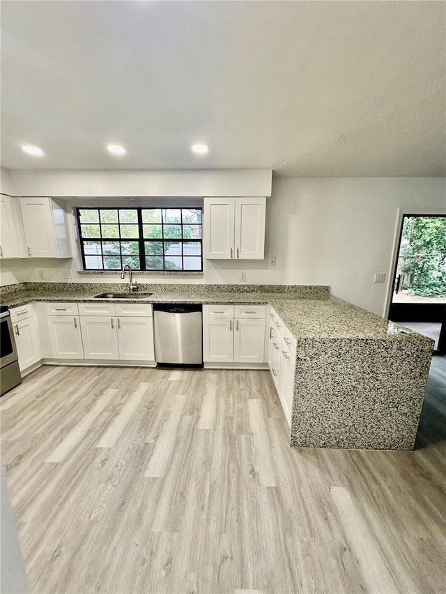 kitchen featuring white cabinets, stainless steel appliances, kitchen peninsula, and light stone counters