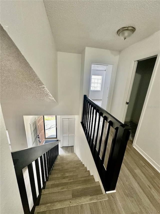 stairs featuring wood-type flooring and a textured ceiling