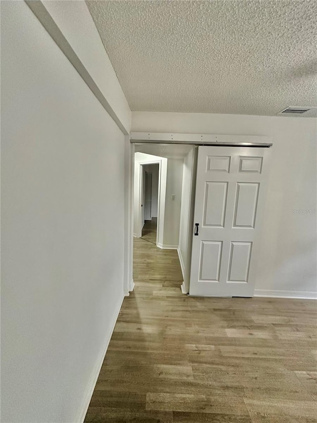 hallway with hardwood / wood-style floors and a textured ceiling