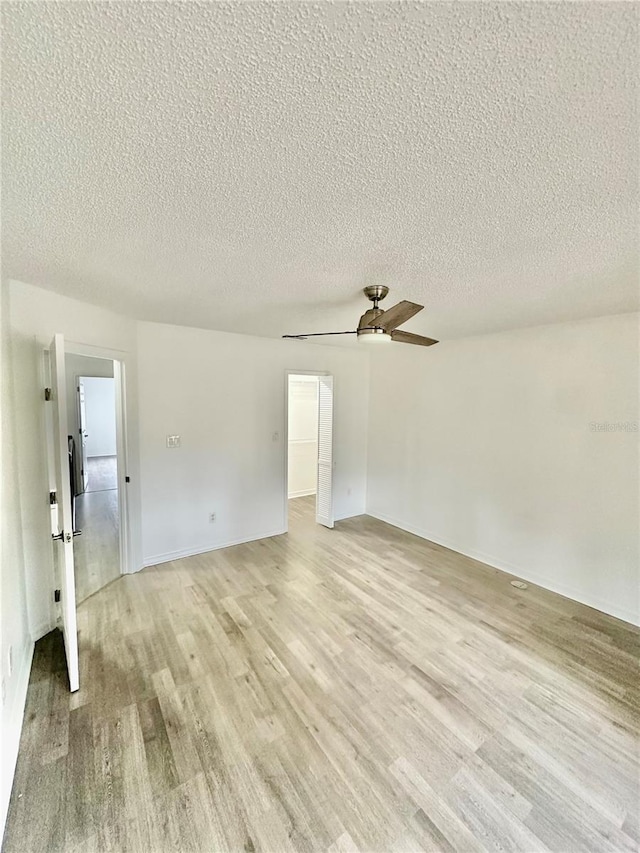 spare room featuring a textured ceiling, light hardwood / wood-style flooring, and ceiling fan