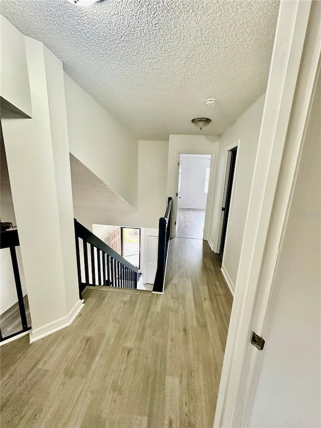 hallway featuring light hardwood / wood-style flooring and a textured ceiling