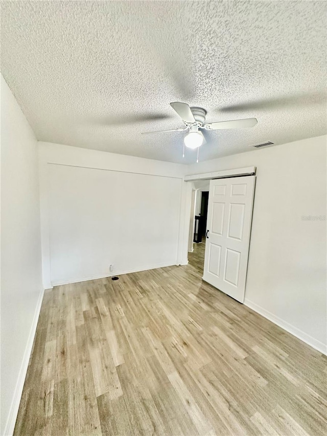 unfurnished bedroom with a textured ceiling, a closet, ceiling fan, and light hardwood / wood-style floors