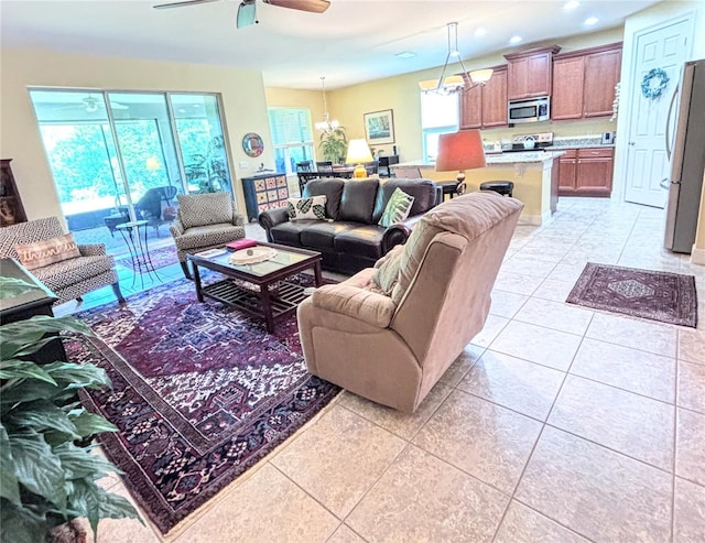 tiled living room featuring ceiling fan with notable chandelier