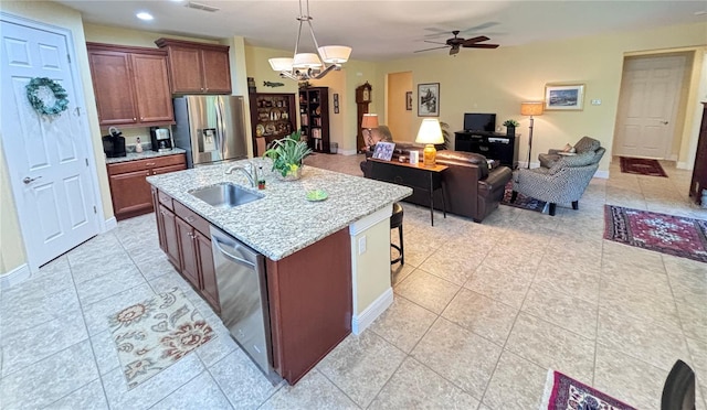 kitchen featuring pendant lighting, ceiling fan with notable chandelier, stainless steel appliances, light tile floors, and sink