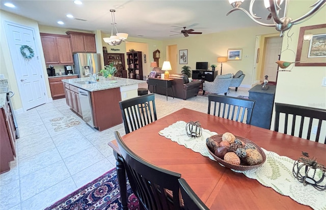 tiled dining area with ceiling fan with notable chandelier and sink