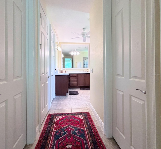 corridor featuring sink and light tile floors