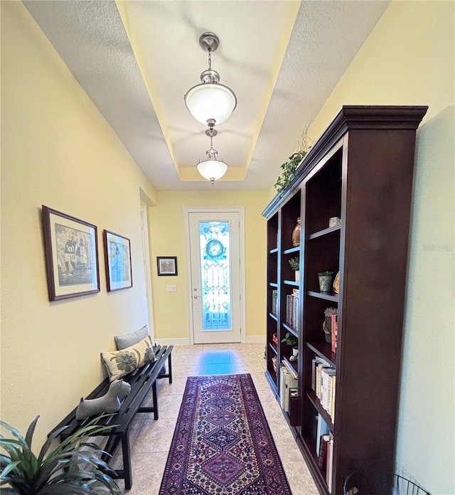 sitting room with a raised ceiling and tile floors