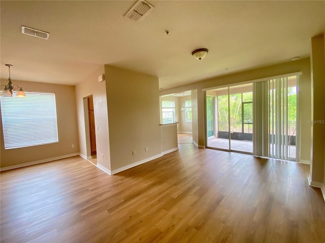 spare room featuring hardwood / wood-style floors and a chandelier