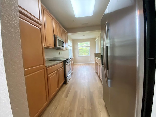 kitchen featuring pendant lighting, light hardwood / wood-style flooring, and stainless steel appliances