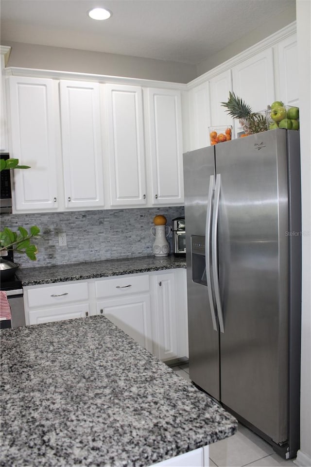 kitchen featuring tasteful backsplash, white cabinetry, light tile flooring, stainless steel fridge with ice dispenser, and dark stone countertops