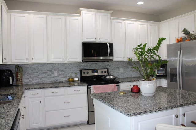 kitchen with appliances with stainless steel finishes, tasteful backsplash, a center island, and white cabinetry