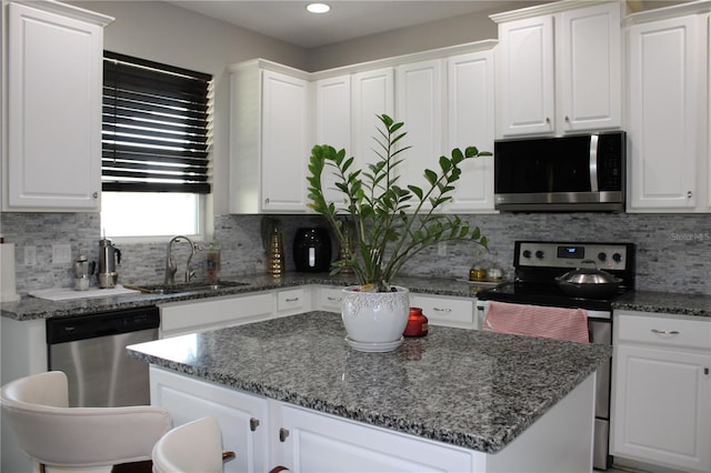 kitchen with white cabinets, a center island, tasteful backsplash, and stainless steel appliances