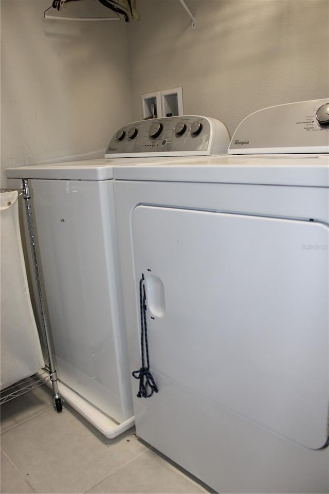 clothes washing area with light tile flooring, hookup for a washing machine, and washer and dryer