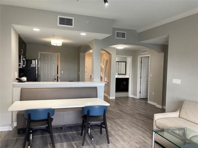 kitchen featuring kitchen peninsula, wood-type flooring, stainless steel appliances, and a breakfast bar