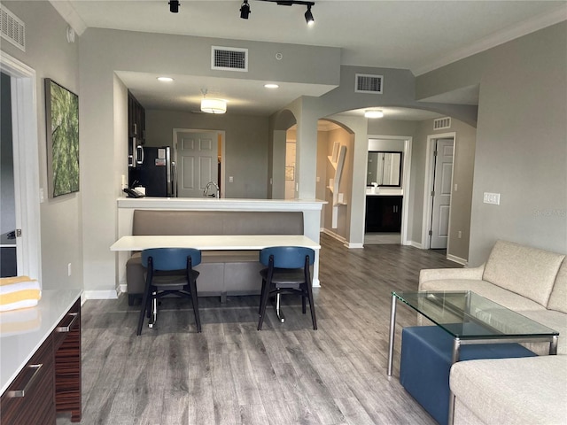 kitchen with rail lighting, kitchen peninsula, black fridge, and hardwood / wood-style floors