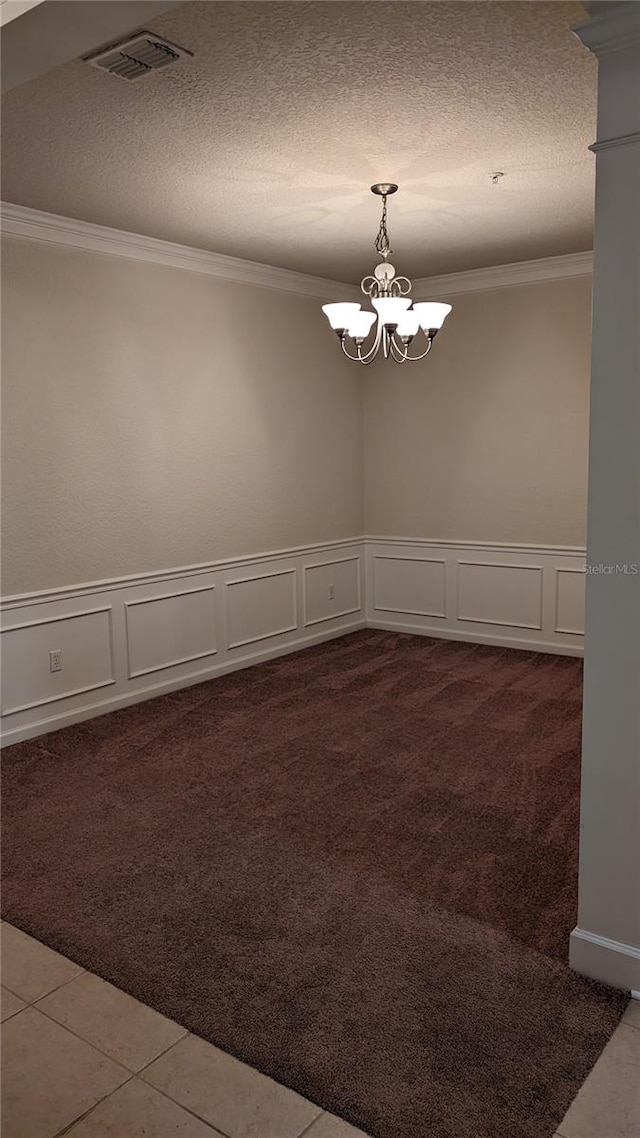 spare room featuring dark carpet, an inviting chandelier, and ornamental molding