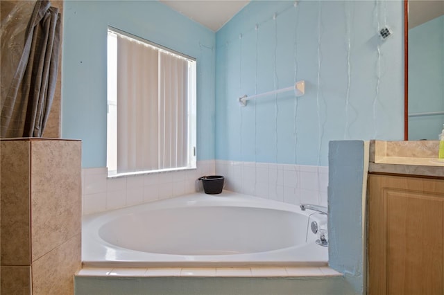 bathroom featuring tiled tub and vanity