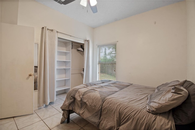 tiled bedroom with a textured ceiling, ceiling fan, and a closet