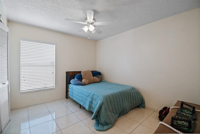 bedroom featuring multiple windows, ceiling fan, light tile patterned floors, and a textured ceiling