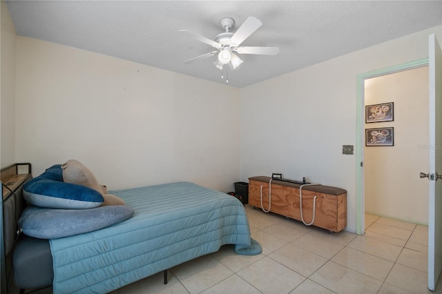 tiled bedroom with ceiling fan and a textured ceiling