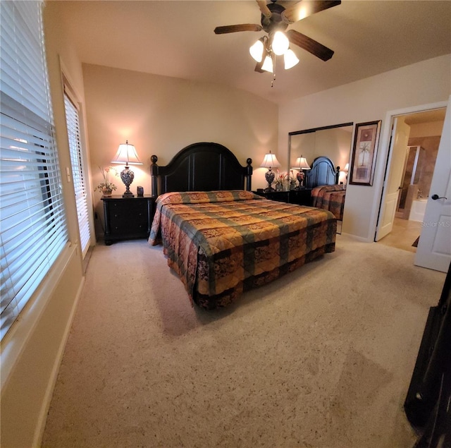 carpeted bedroom with ensuite bath and ceiling fan