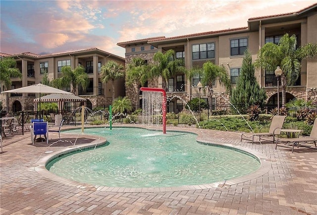 pool at dusk with a patio and pool water feature