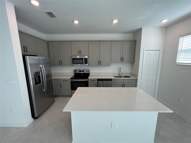 kitchen with sink, appliances with stainless steel finishes, light tile floors, and a kitchen island