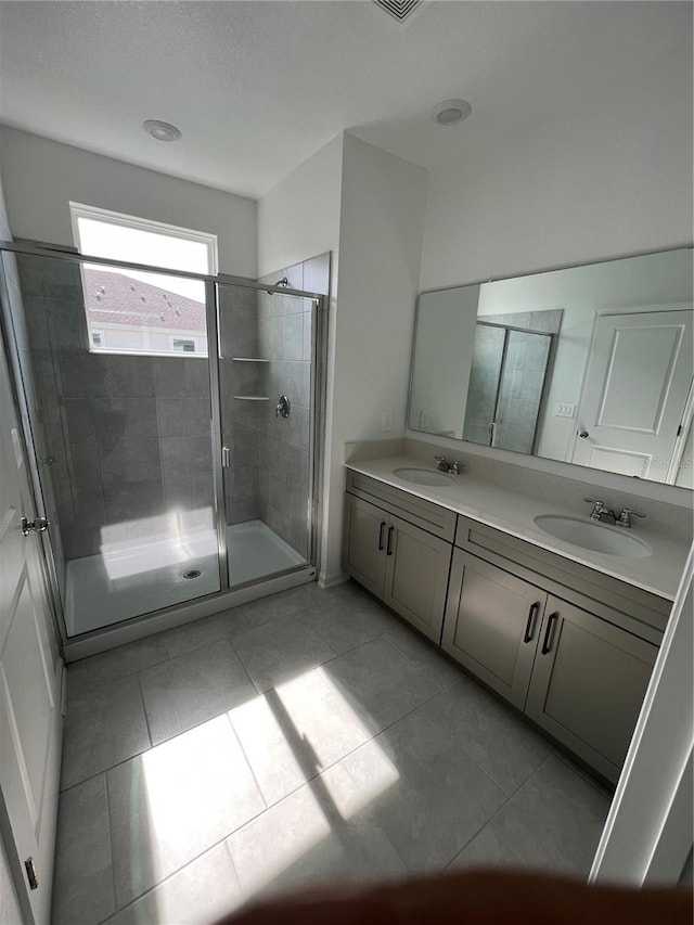 bathroom with a shower with door, tile floors, and dual vanity