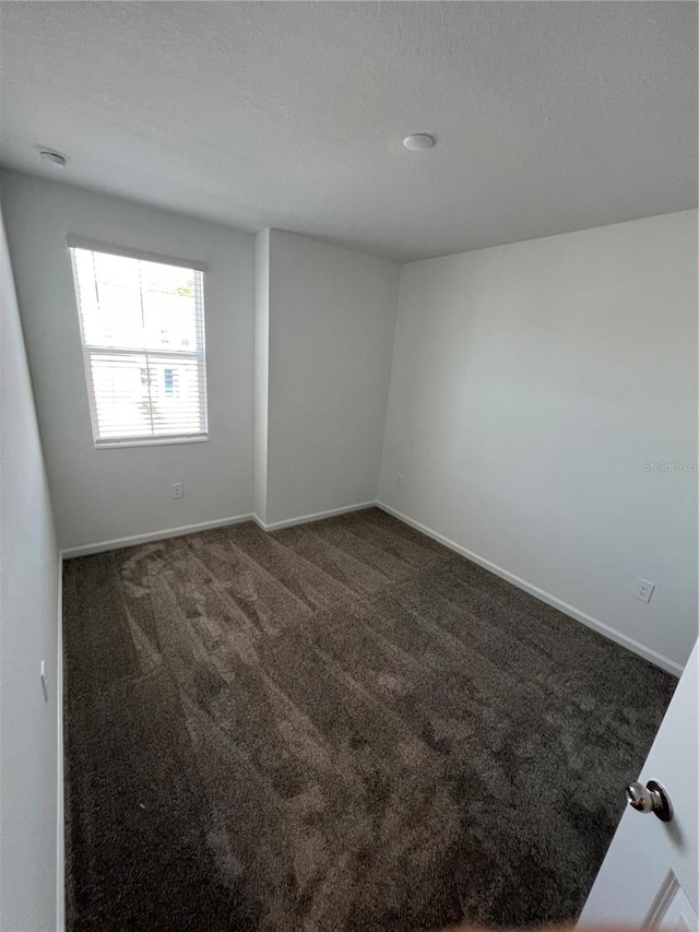 spare room featuring dark colored carpet