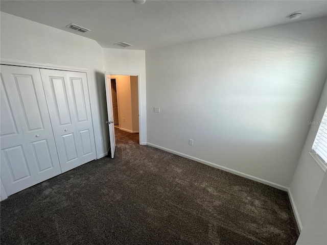 unfurnished bedroom with a closet and dark colored carpet