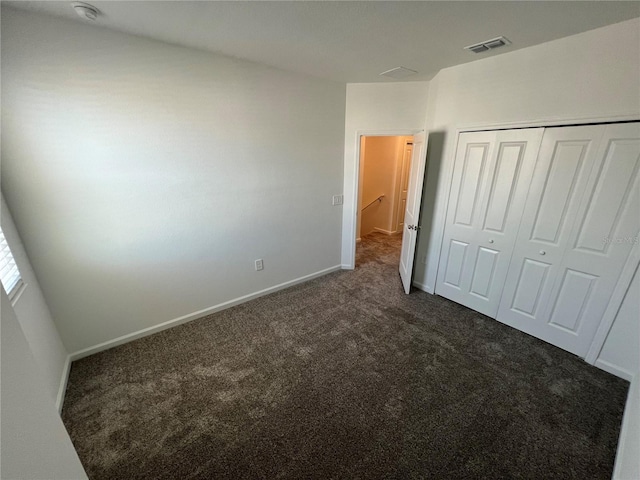 unfurnished bedroom featuring dark colored carpet and a closet