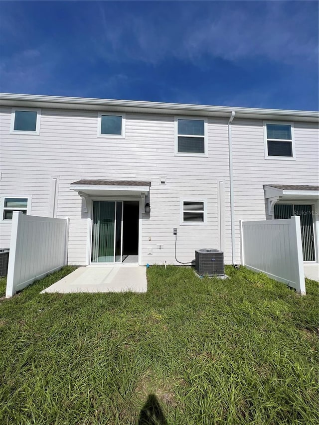 rear view of house featuring a patio, a yard, and central AC