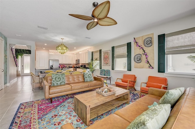 tiled living room featuring ceiling fan with notable chandelier