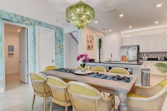 kitchen featuring stainless steel fridge, light tile patterned floors, white cabinetry, and sink