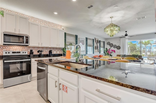 kitchen with stainless steel appliances, white cabinetry, and dark stone counters