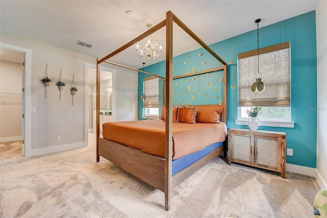 bedroom with a notable chandelier, carpet floors, a textured ceiling, and ensuite bath