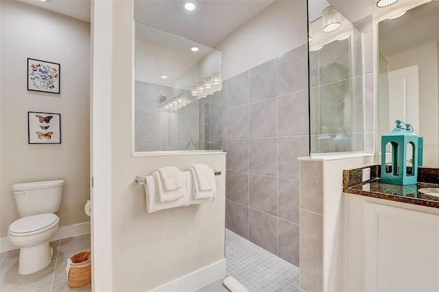 bathroom with tile patterned floors, vanity, toilet, and a tile shower