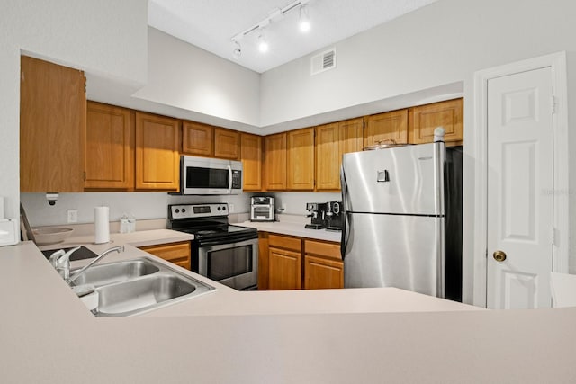 kitchen featuring appliances with stainless steel finishes, sink, and track lighting