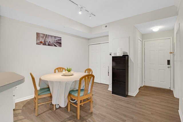 dining space featuring wood-type flooring and rail lighting