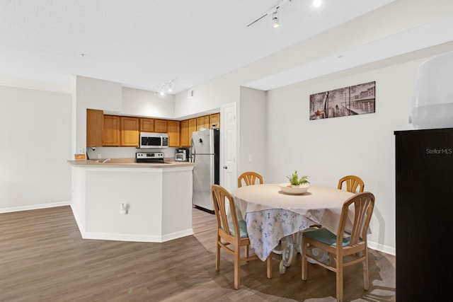 dining room with rail lighting and wood-type flooring