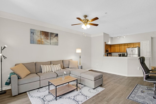 living room featuring ceiling fan, a textured ceiling, light wood-type flooring, crown molding, and rail lighting