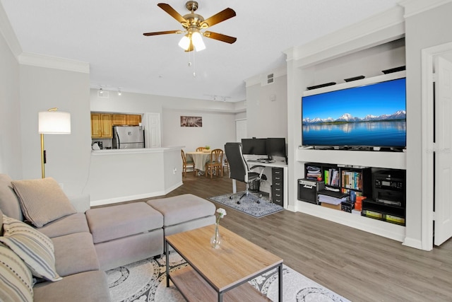 living room featuring ornamental molding, rail lighting, ceiling fan, and light wood-type flooring