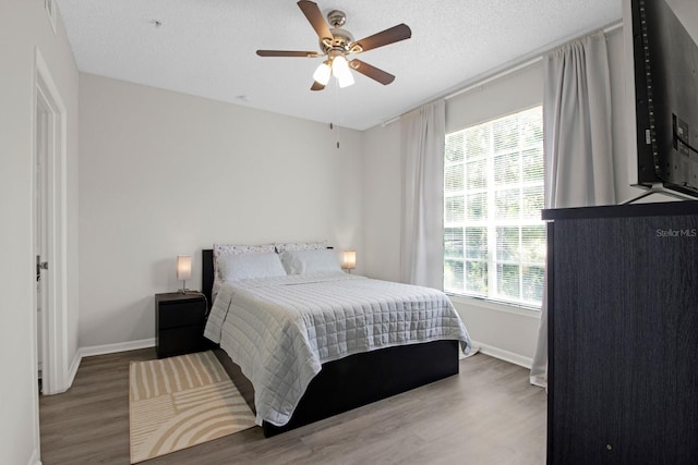 bedroom featuring a textured ceiling, ceiling fan, and hardwood / wood-style flooring